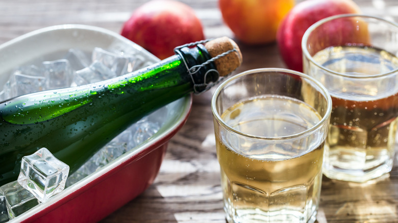 two glasses of cider bottle and apples