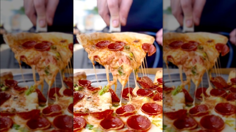 Person picking up a slice of pizza at Fumo NYC