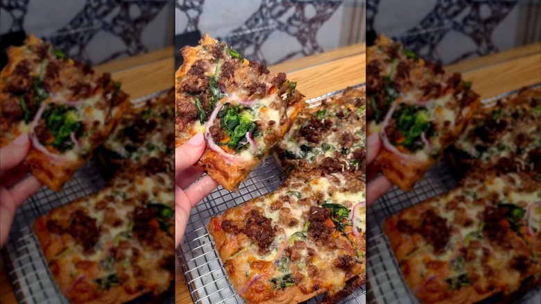 Person holding slice of Modern Bread & Bagel pizza