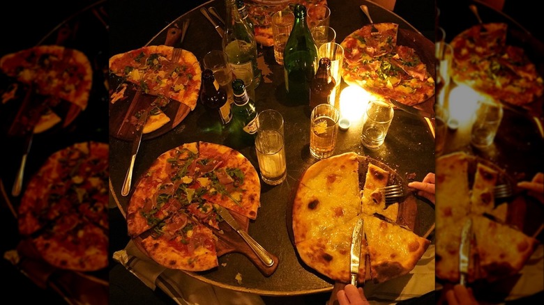 Dining table at Uva Next Door with multiple pizzas and drinks