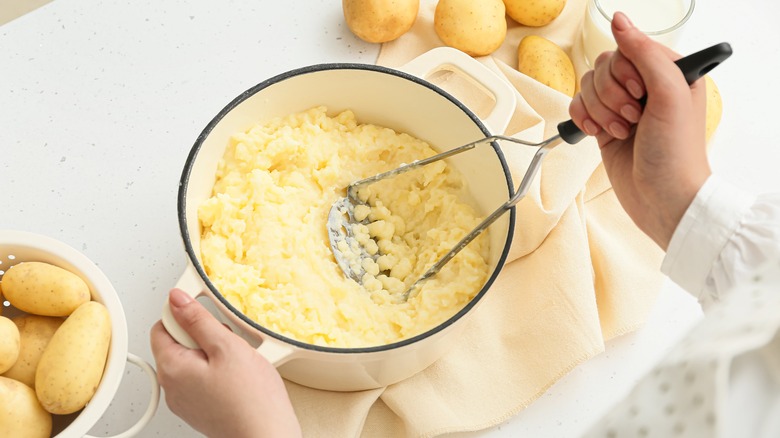 person mashing potatoes in a pot