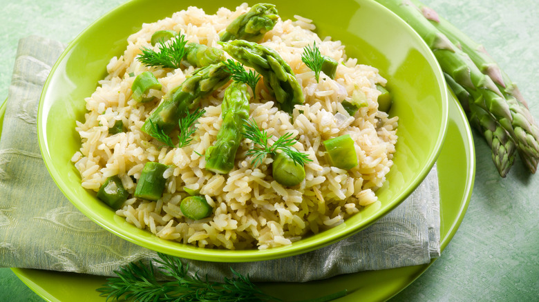 Asparagus Risotto in a green bowl with asparagus on the side