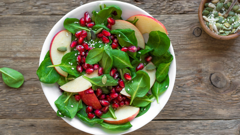 A bowl of fresh spinach, apple and pomegranate