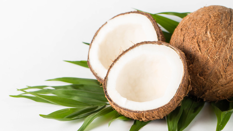 A halved coconut next to a whole one