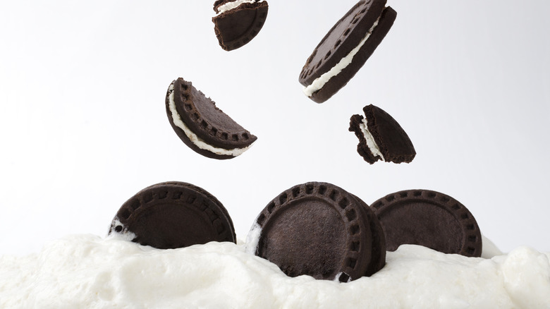 chocolate sandwich cookies falling into cream