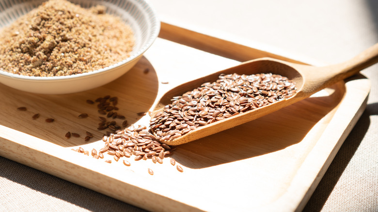 A bowl of ground flaxseed alongside whole flaxseed