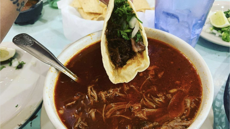 Birria taco dipping in consomme