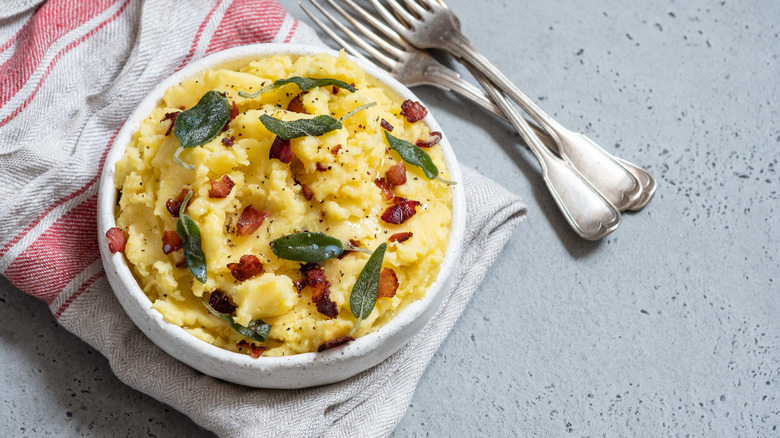 Bowl of mashed potatoes butter, bacon, sage leaves blue