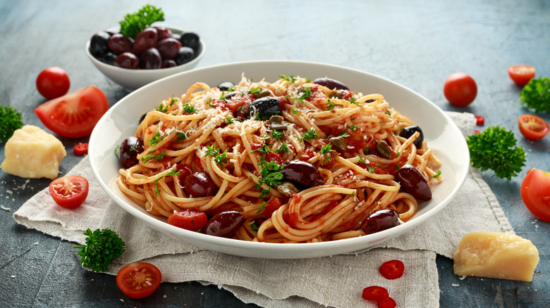 a bowl of pasta puttanesca with olives, garlic, and tomatoes