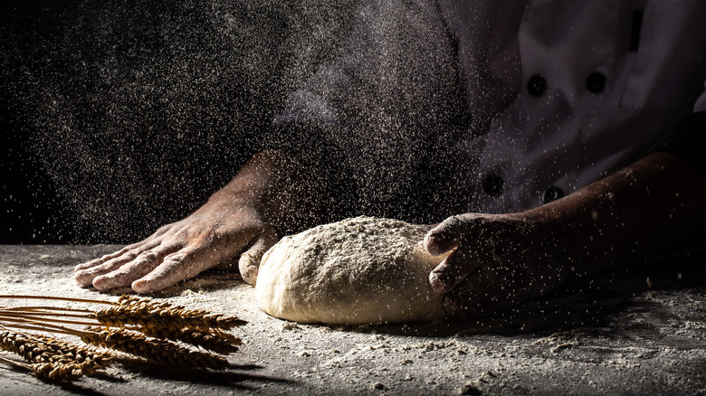 Hands placing dough on countertop