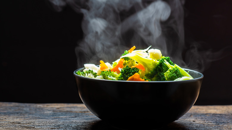 Vegetables steaming in black bowl