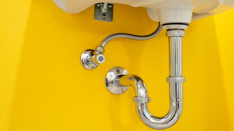 Bathroom drain against yellow wall