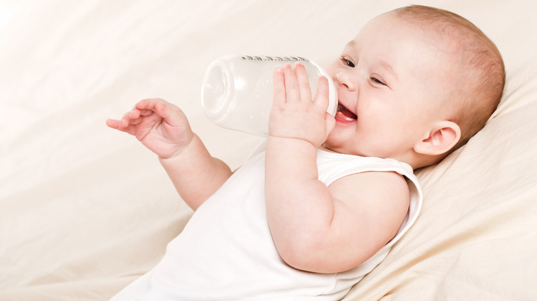 Smiling baby holding bottle