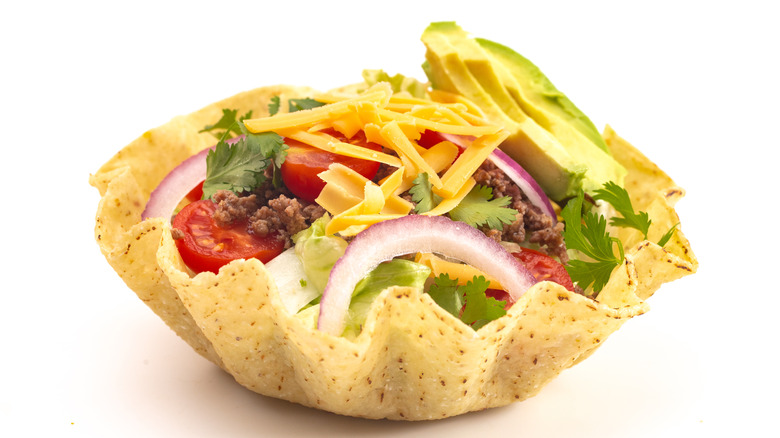 Tortilla bowl with avocado, cheese, and onion