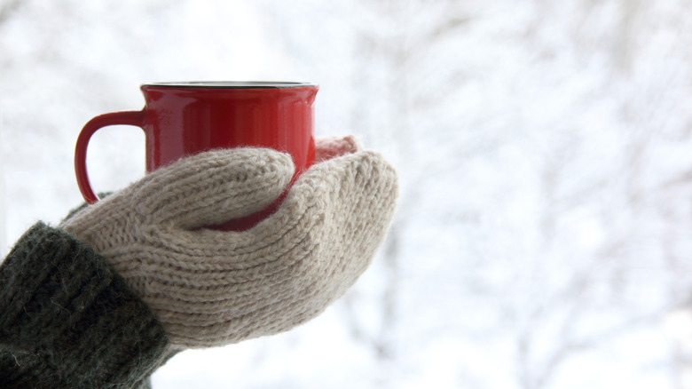 mittened hands holding a mug