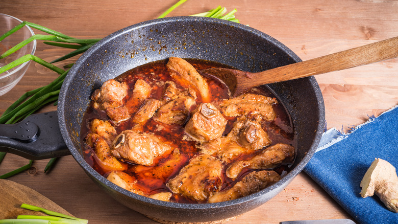braised pork in wok with wooden spoon