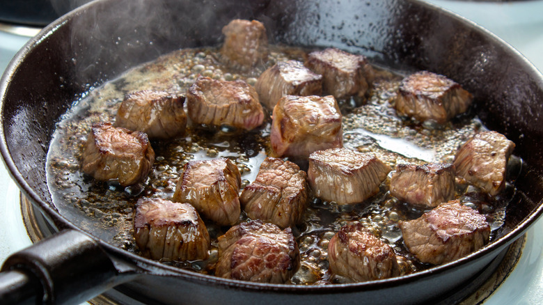 Chunks of beef searing in a pan.