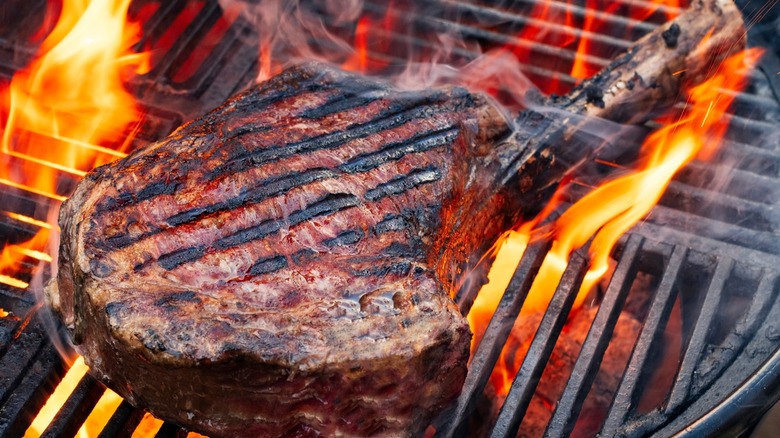 A cowboy steak on the grill with flames