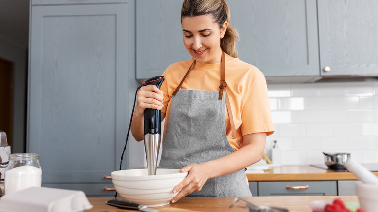 A woman using an immersion blender