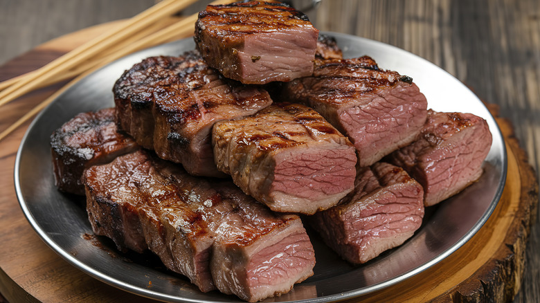 a pile of cooked leftover steaks on a silver platter