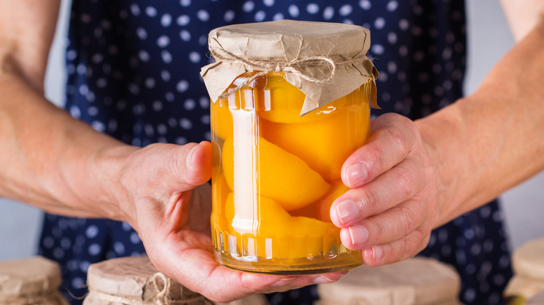 Person holding a jar of peaches