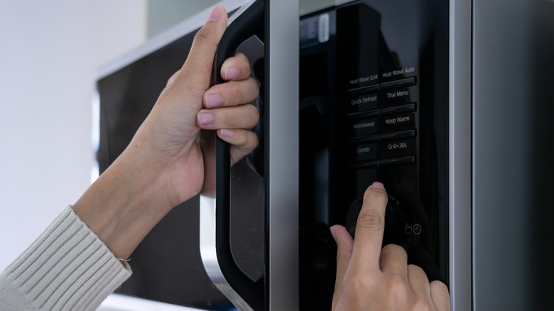 hands of a person programming a microwave