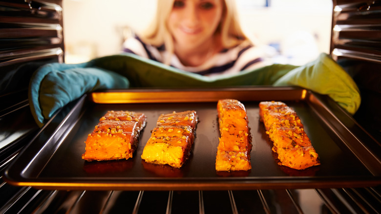 putting salmon fillets into oven