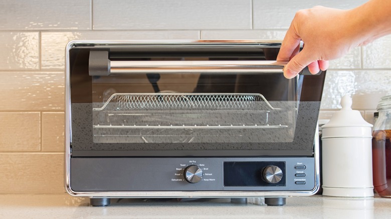 Hand pulling down countertop convection oven