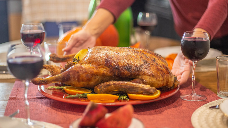 woman setting a turkey on the table with wine