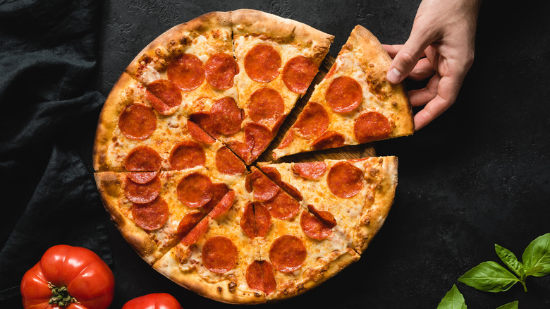 Hand reaching for pepperoni pizza