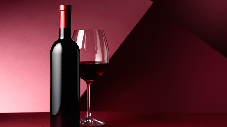 An unbranded wine bottle with a glass of red wine