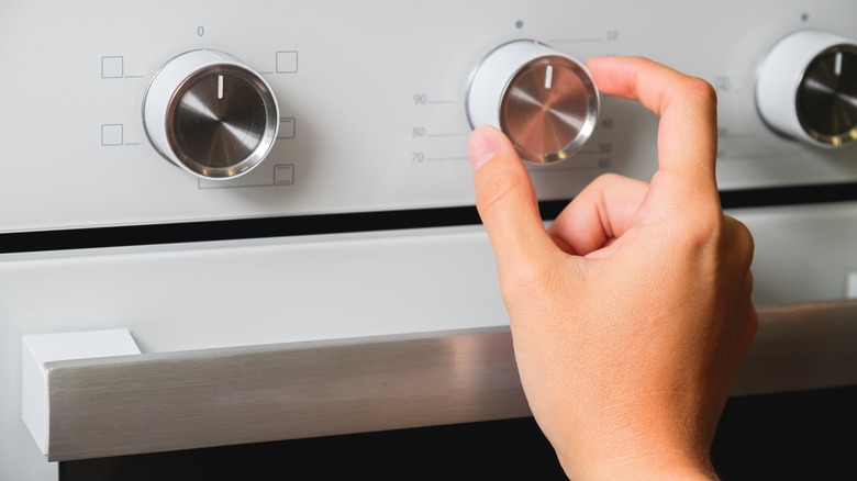 Person adjusting knob on oven