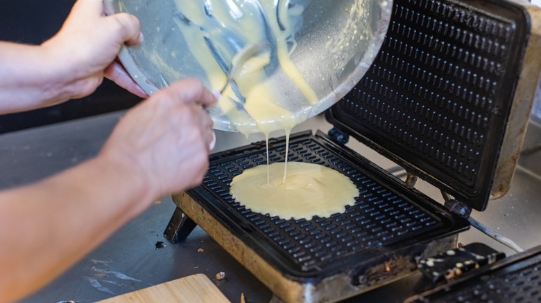 Pouring waffle batter into a waffle iron