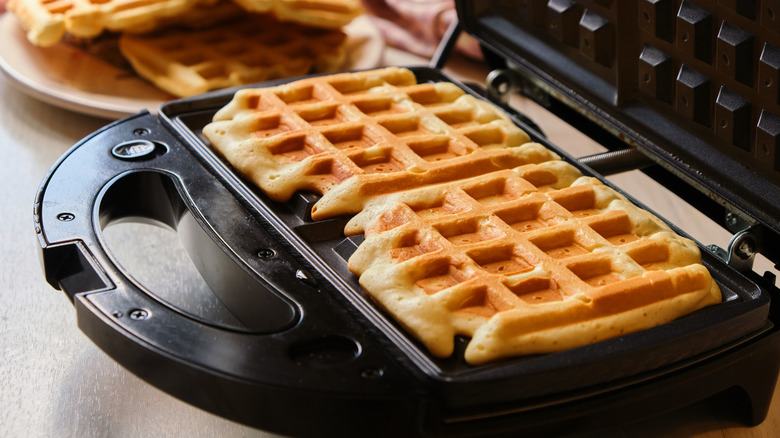 two cooked waffles in a waffle maker