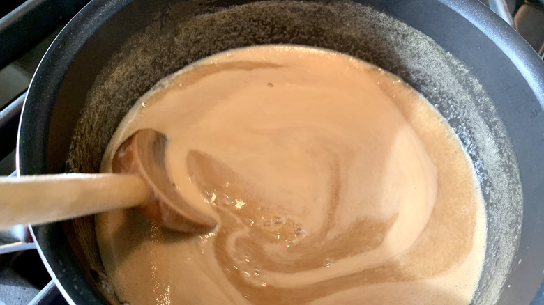 Toffee sauce cooking in a pan with a wooden spoon
