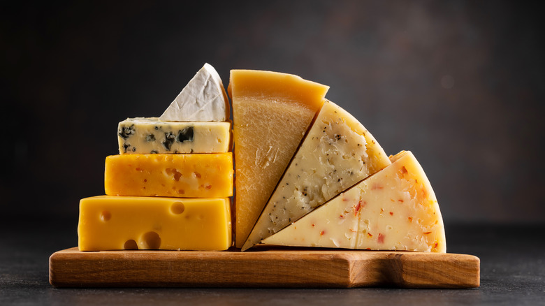 Various cheeses stacked on board