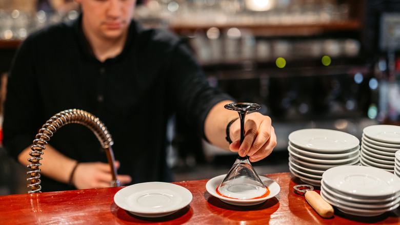 bartender dipping cocktail glass rim into a saucer