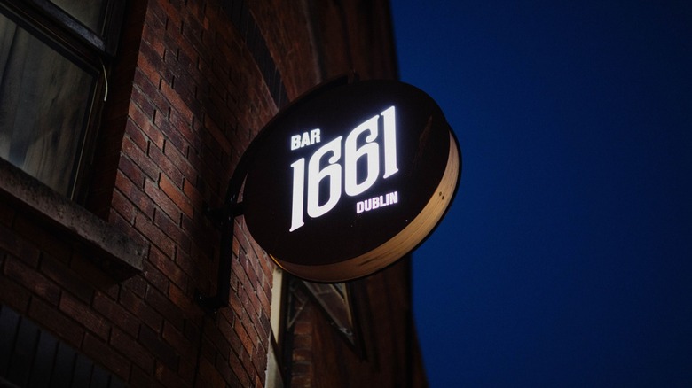 The Bar 1661 sign on the brick building at dusk