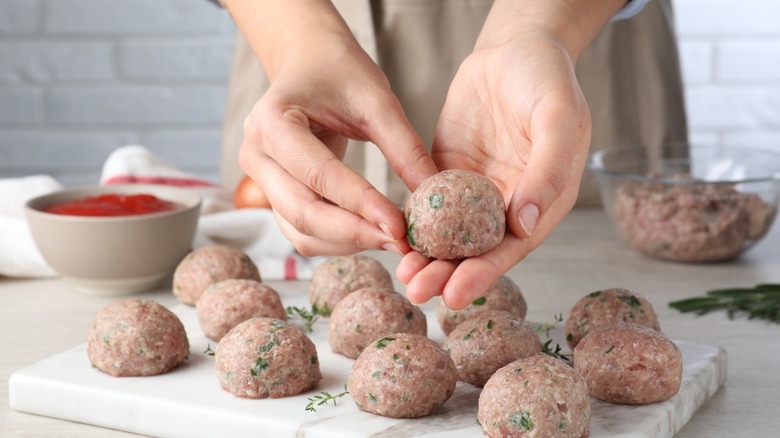 cook making fresh raw meatballs