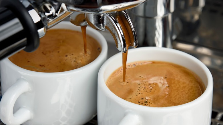 Espresso pouring into white cups