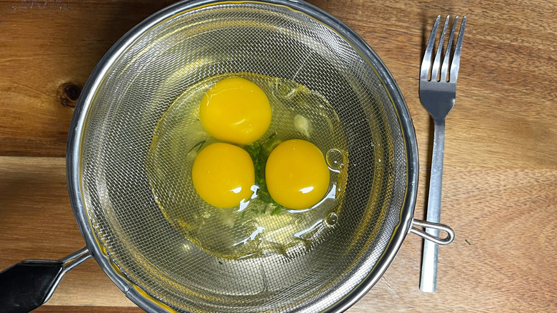 cracked eggs in sieve