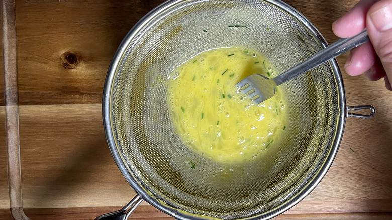 whisking eggs in sieve