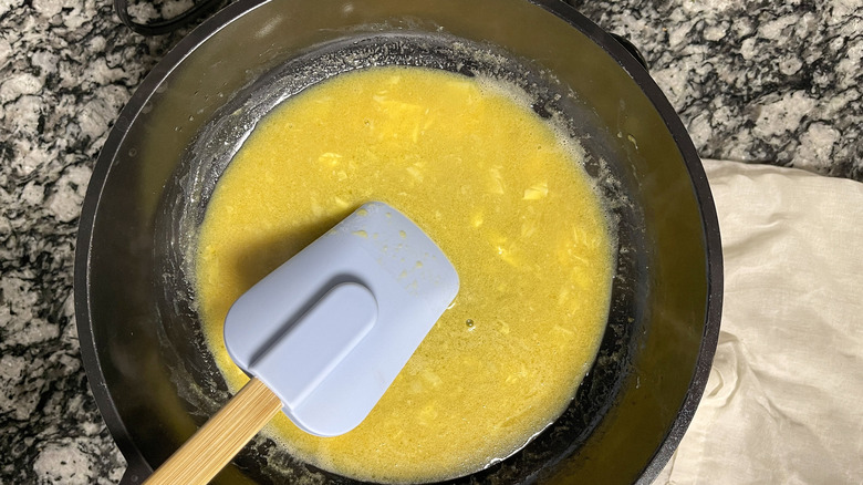 stirring whisked eggs in skillet