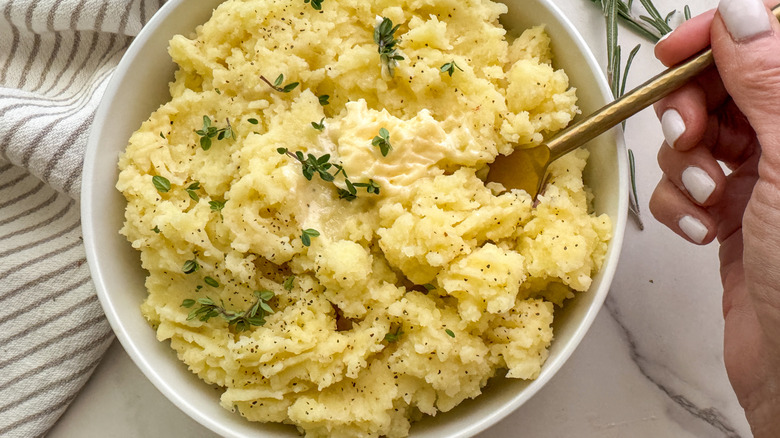 hand with fork in potatoes