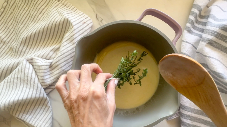 hand adding herbs to pot
