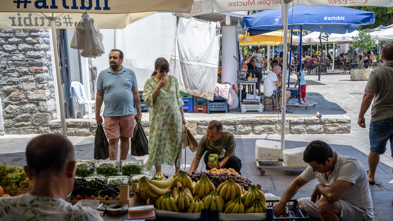 Travelers browse fresh produce from a local stand