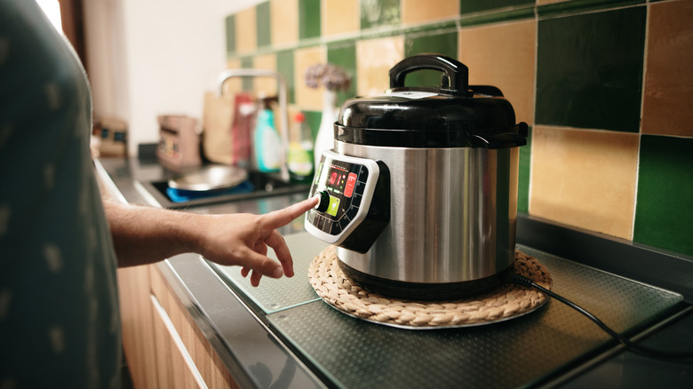 hand pressing slow cooker button