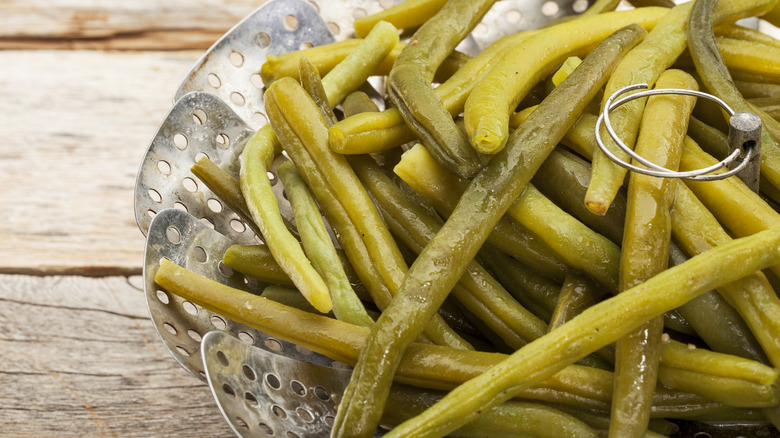 cooked green beans in a metal steamer basket