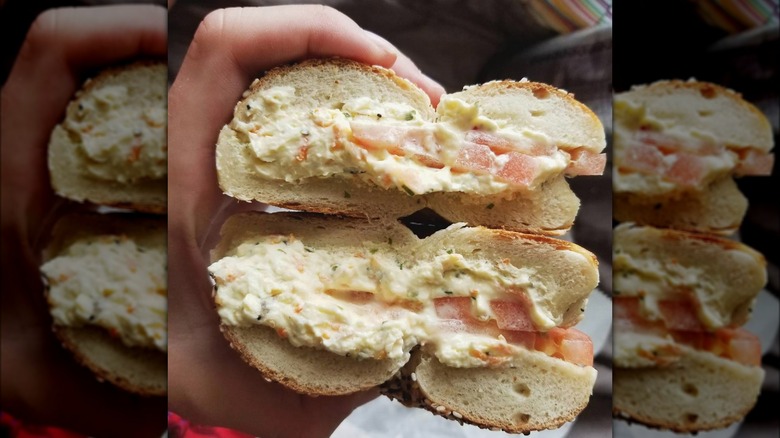 Hand holding halved bagel