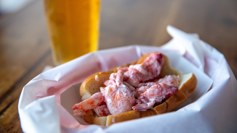 Lobster roll with glass of beer in background